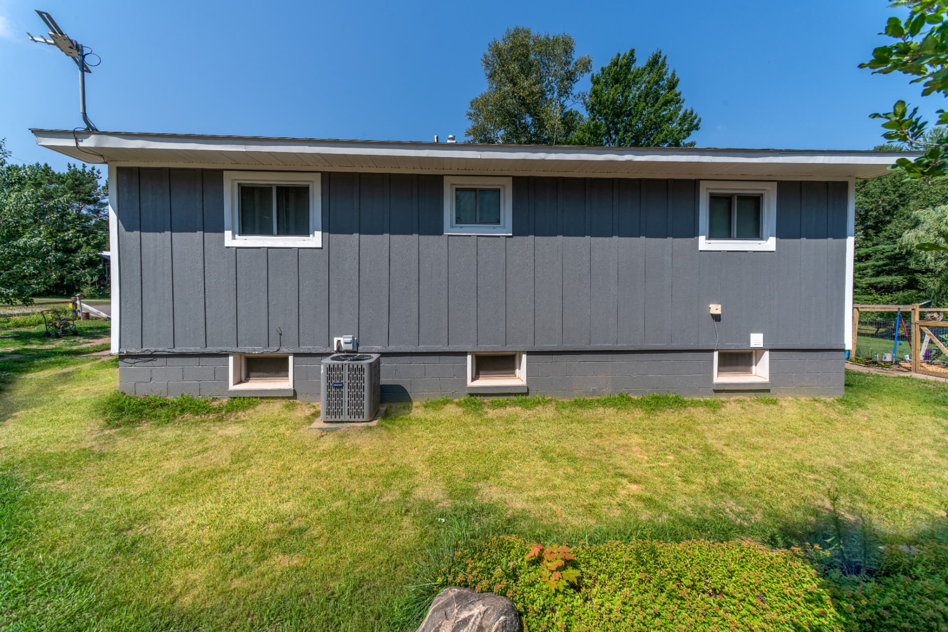 Side elevation of the single story house with gray siding and sliding windows in Marquette County