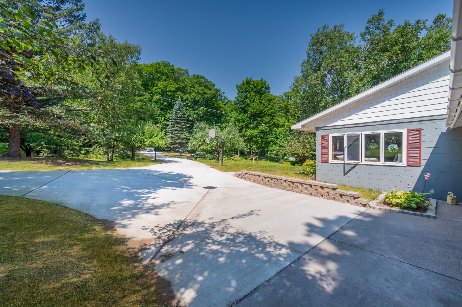 Segmental block retaining wall along a new concrete driveway with drainage grate in Marquette County