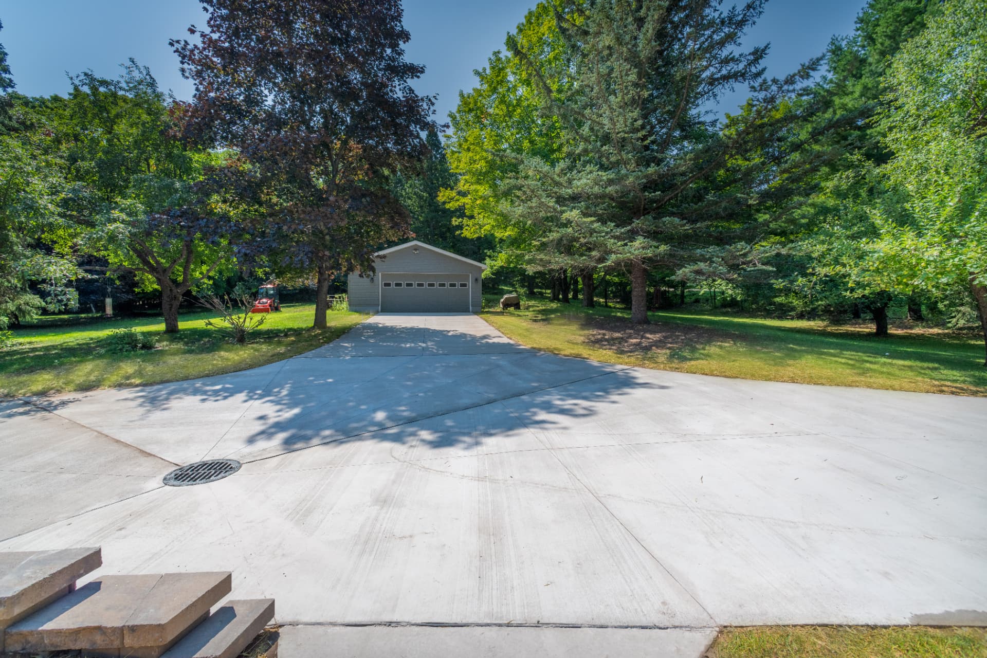 Wide concrete driveway leading to a detached garage with a new catch basin in Marquette, MI