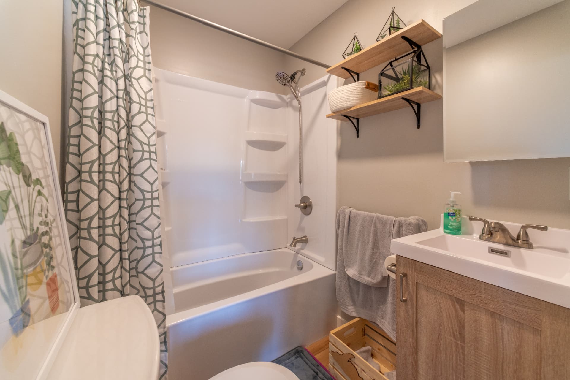 Finished full bathroom with tub shower surround and wood vanity in a Marquette, MI new build
