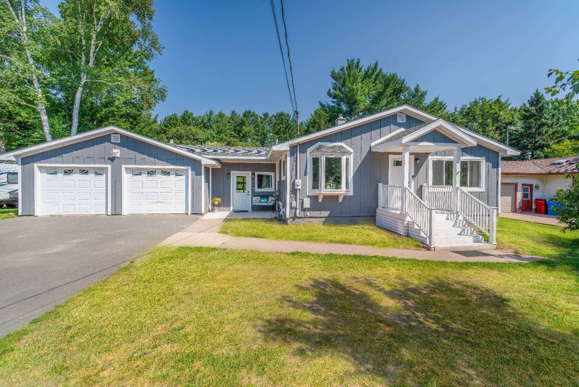 Exterior front view of house and garage with matching gray board and batten siding and a connecting breezeway in Marquette County