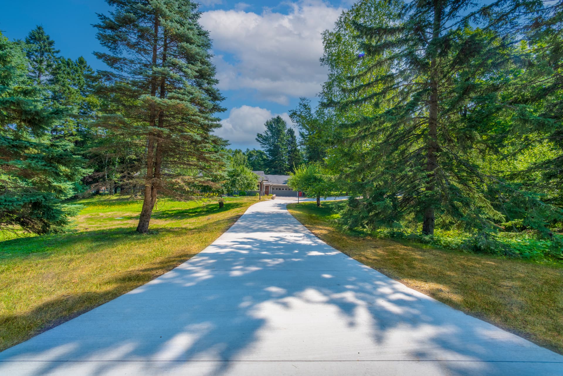 Long concrete driveway with culvert and graded shoulders leading to a home in Marquette, MI