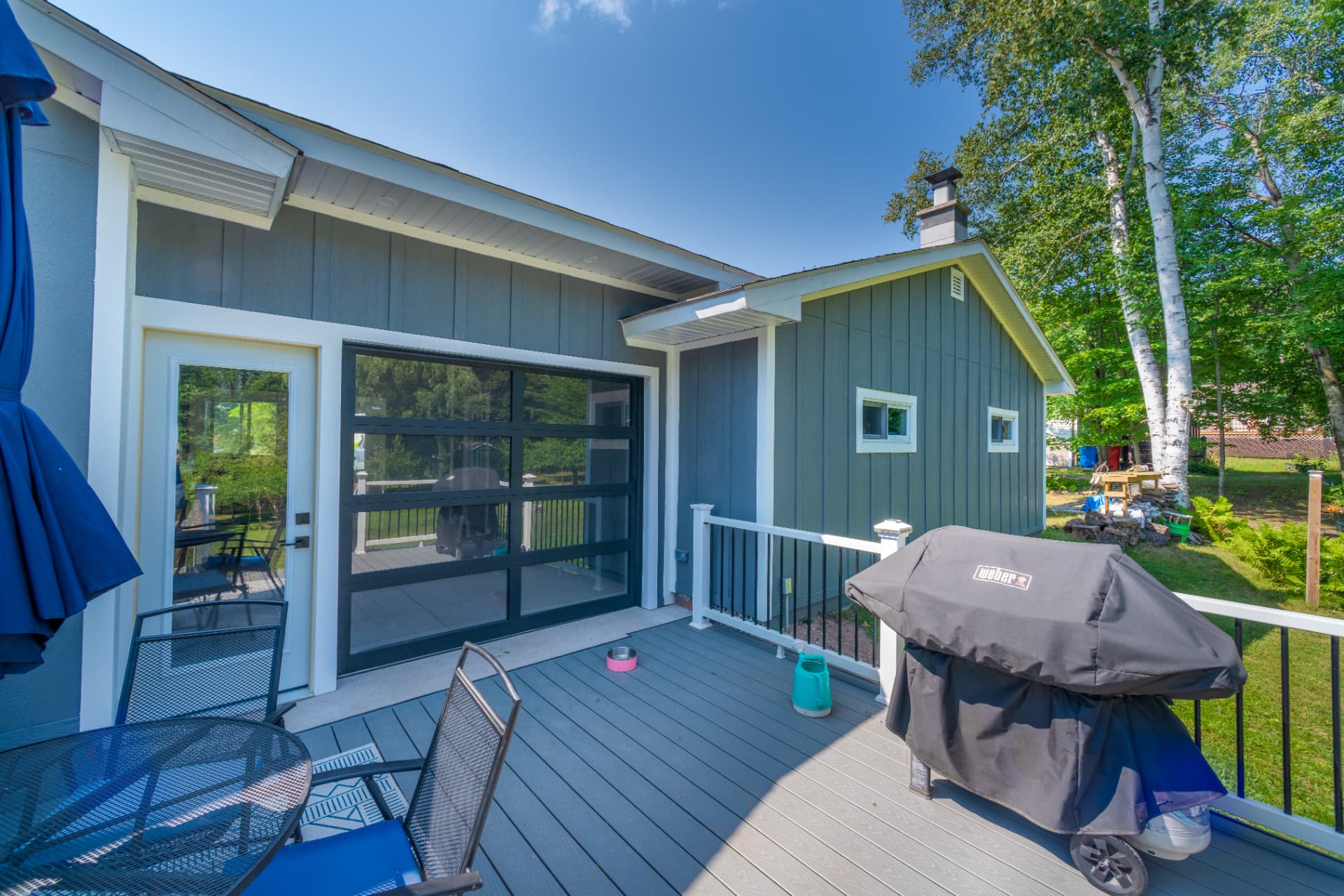 Close up of the black framed glass garage door and white entry door opening onto a deck in Marquette, MI