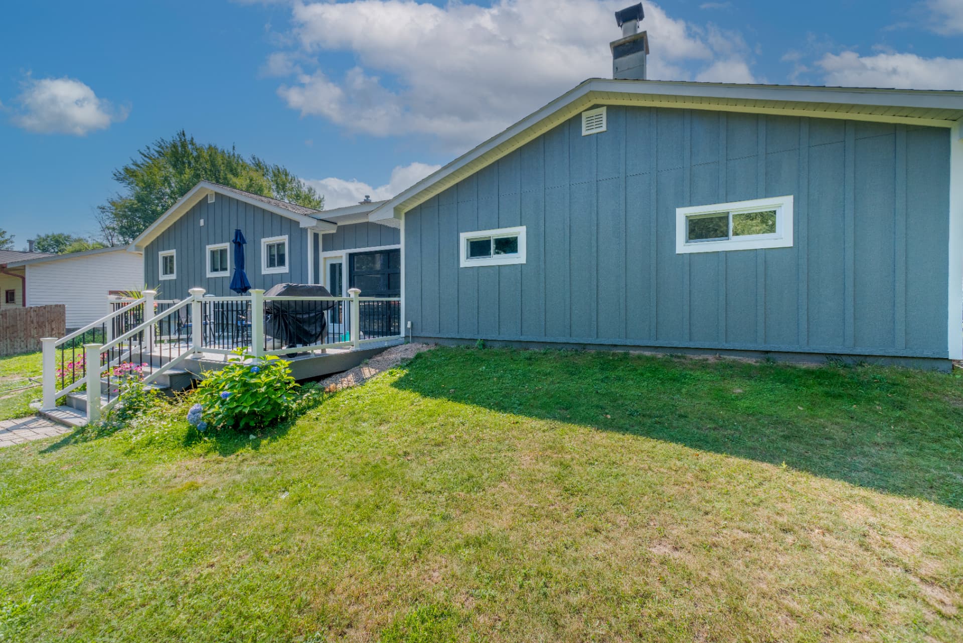Rear exterior view of the house and garage with gray siding and a glass paneled garage door in Marquette County
