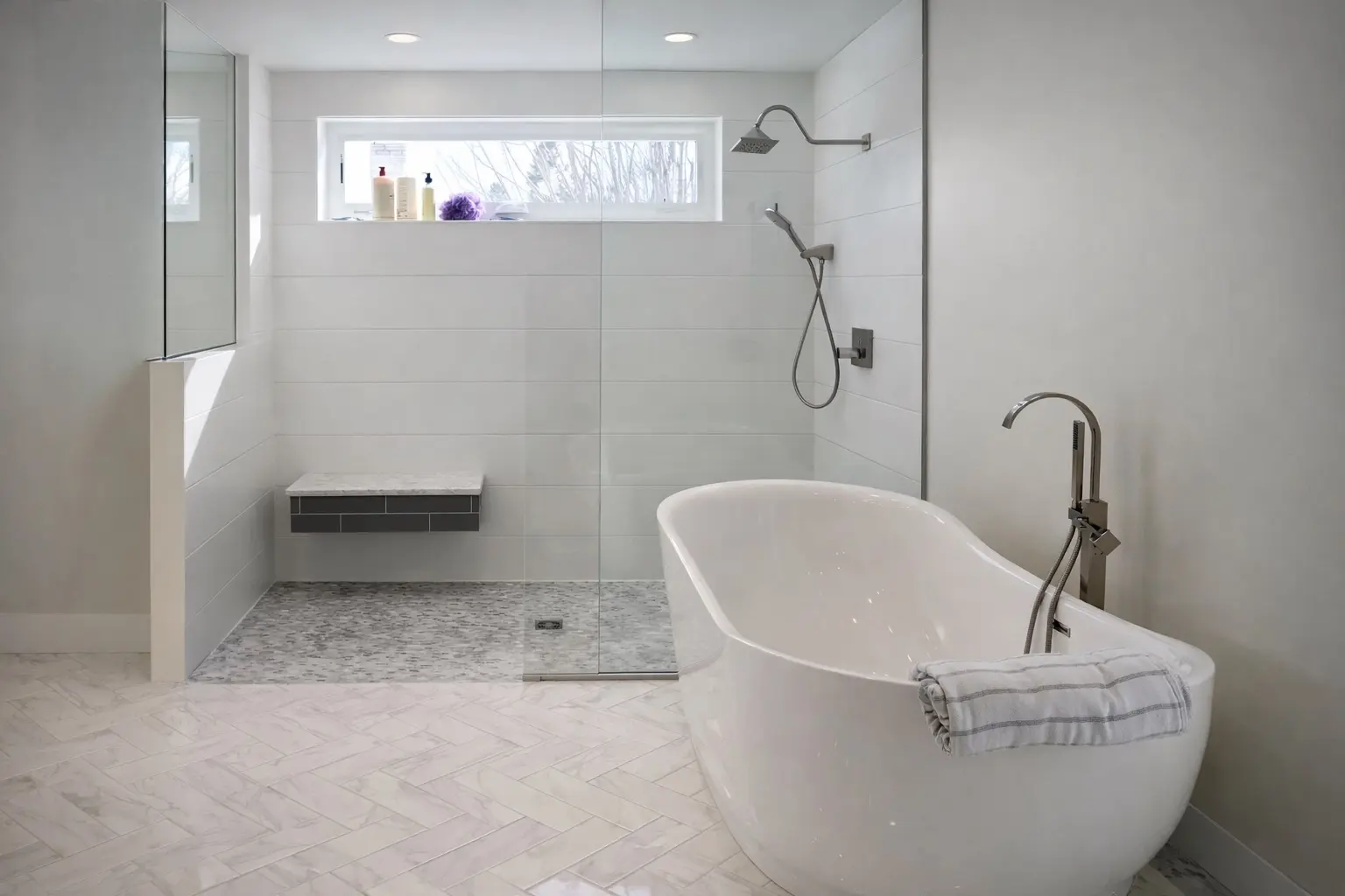 Modern bathroom remodel with freestanding tub, walk-in glass shower, and herringbone tile floor in Marquette, Michigan