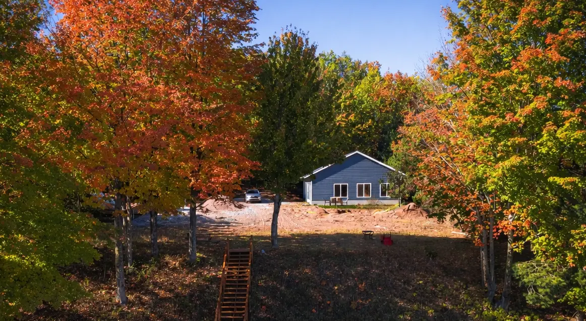 Newly built custom home with blue siding surrounded by vibrant fall foliage in Marquette, Michigan
