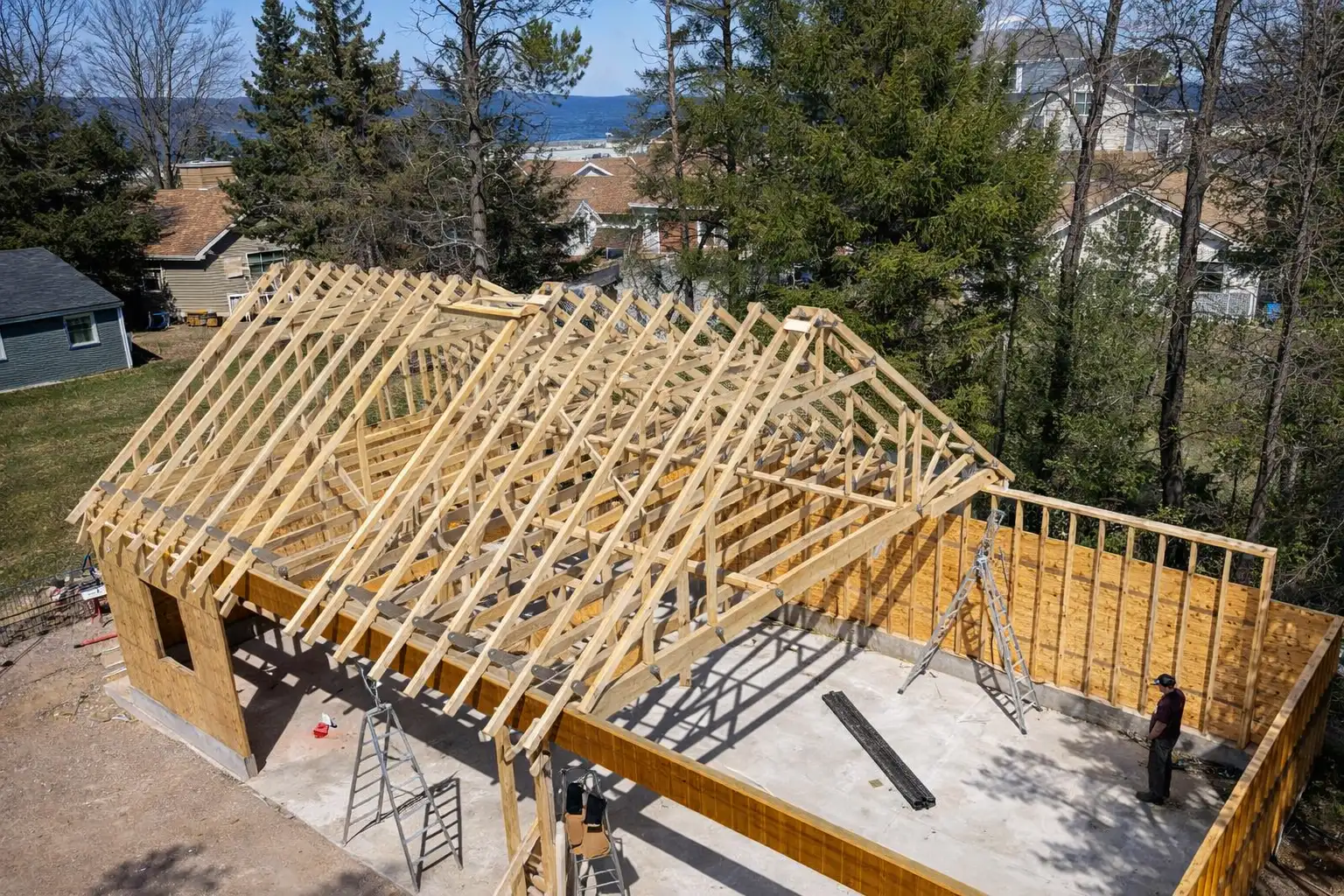 Aerial view of detached garage framing with engineered roof trusses on a concrete slab in a Marquette, Michigan neighborhood