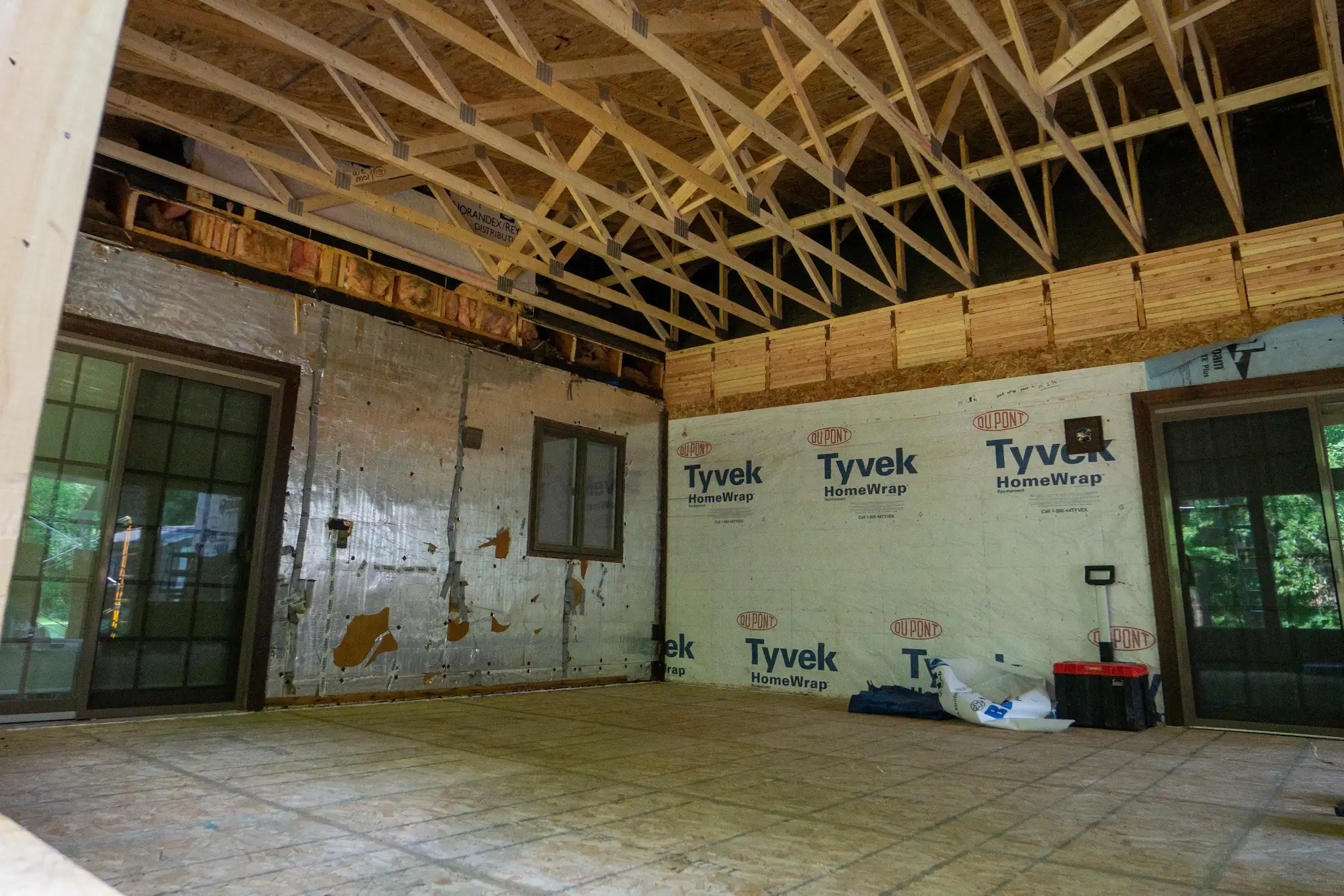 Interior structural framing with exposed roof trusses and Tyvek housewrap during a major home renovation in Marquette, Michigan