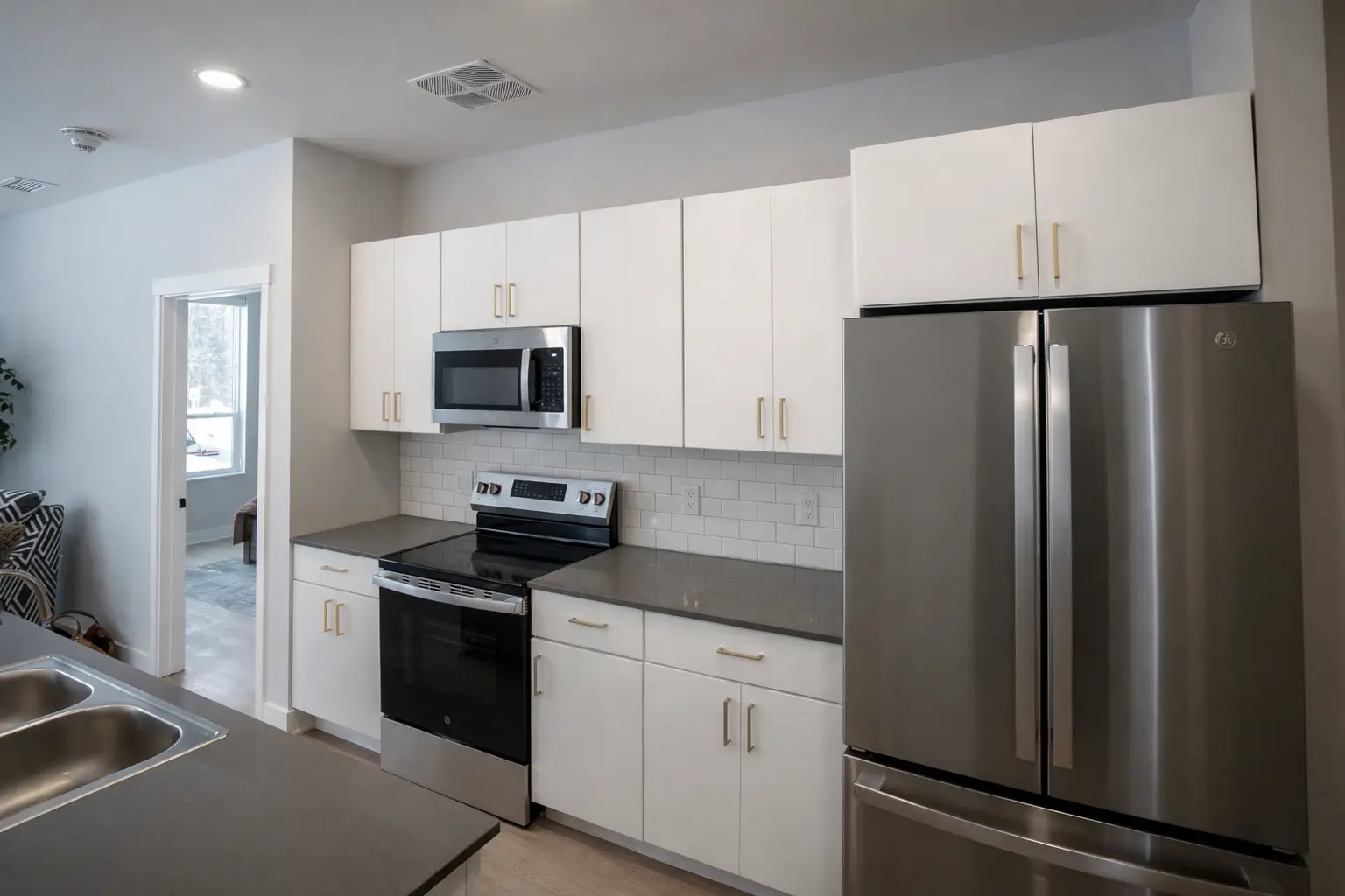 Modern kitchen with white cabinets, gold hardware, subway tile backsplash, and stainless steel appliances in Marquette, Michigan