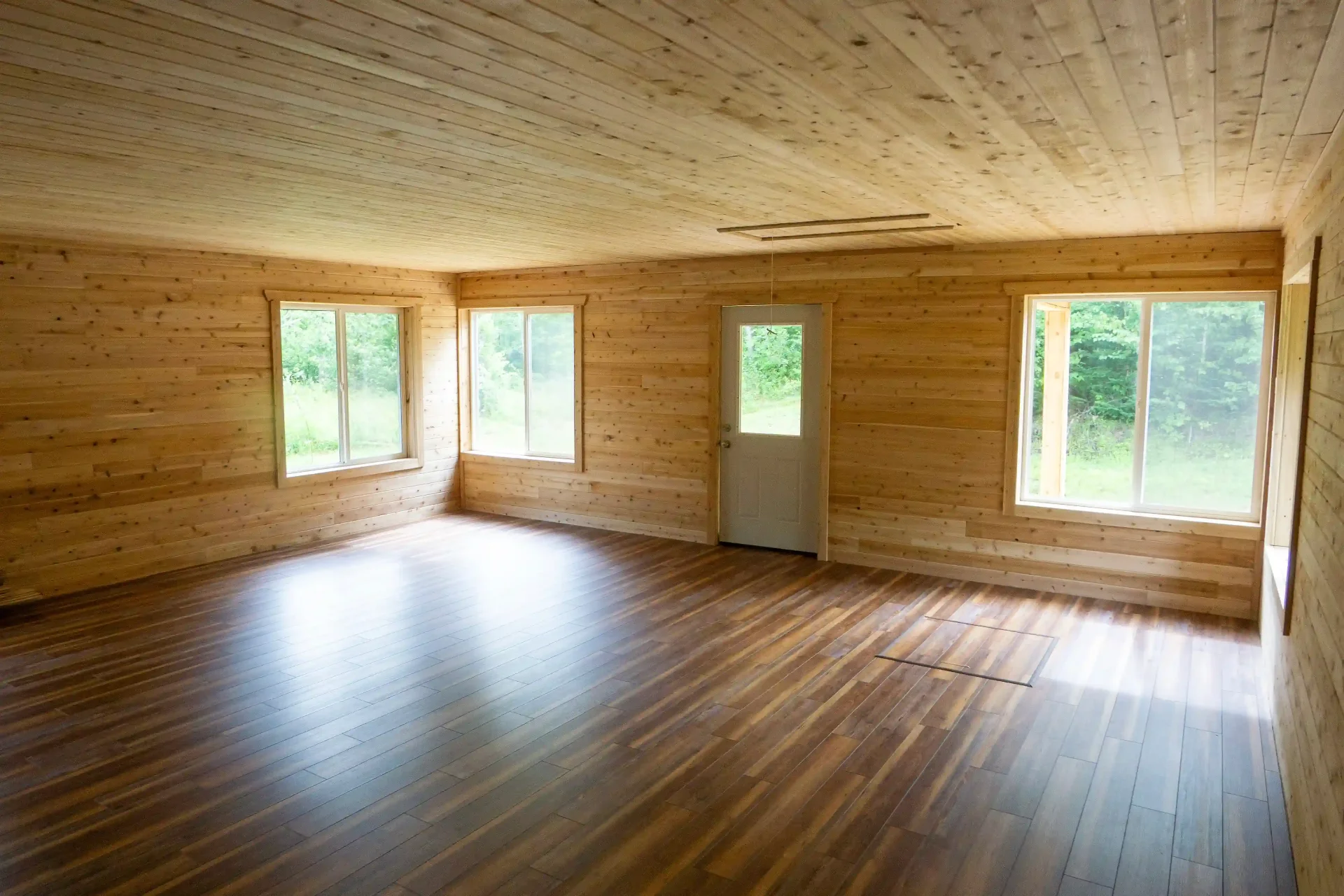 Newly remodeled room with cedar plank walls, hardwood floors, and natural light in Marquette, Michigan