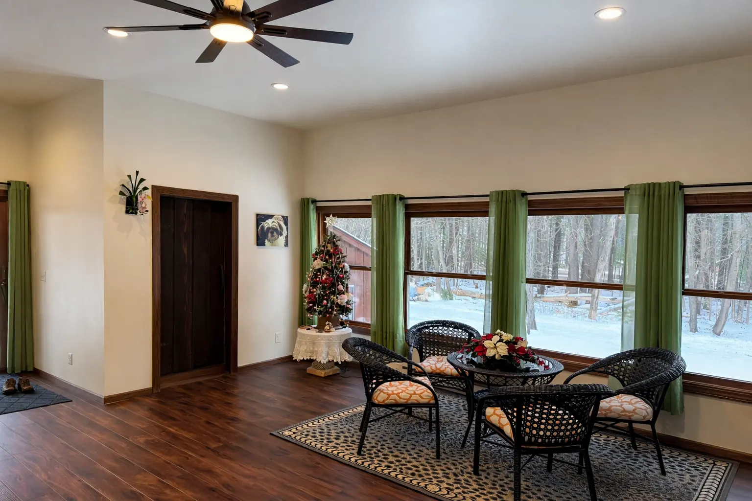 Finished sunroom addition with dark hardwood floors, large windows overlooking a snowy wooded yard in Marquette, Michigan